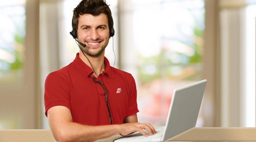 man wearing red clothes calling with headphones and a computer